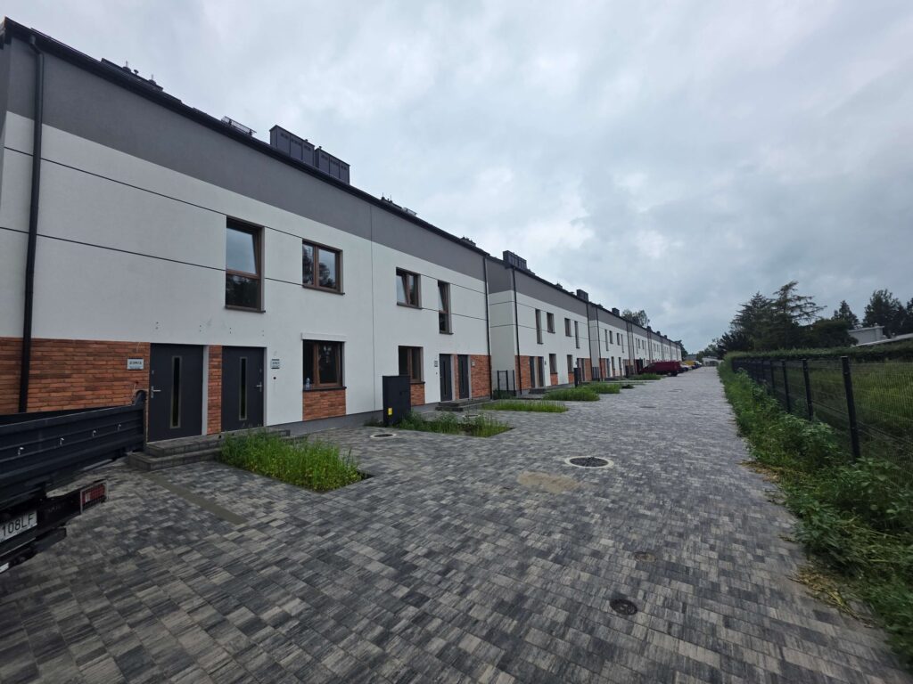 Zrealizowana inwestycja Norwida w Radzyminie — szereg domów z elewacją biało-grafitową i cegłą
